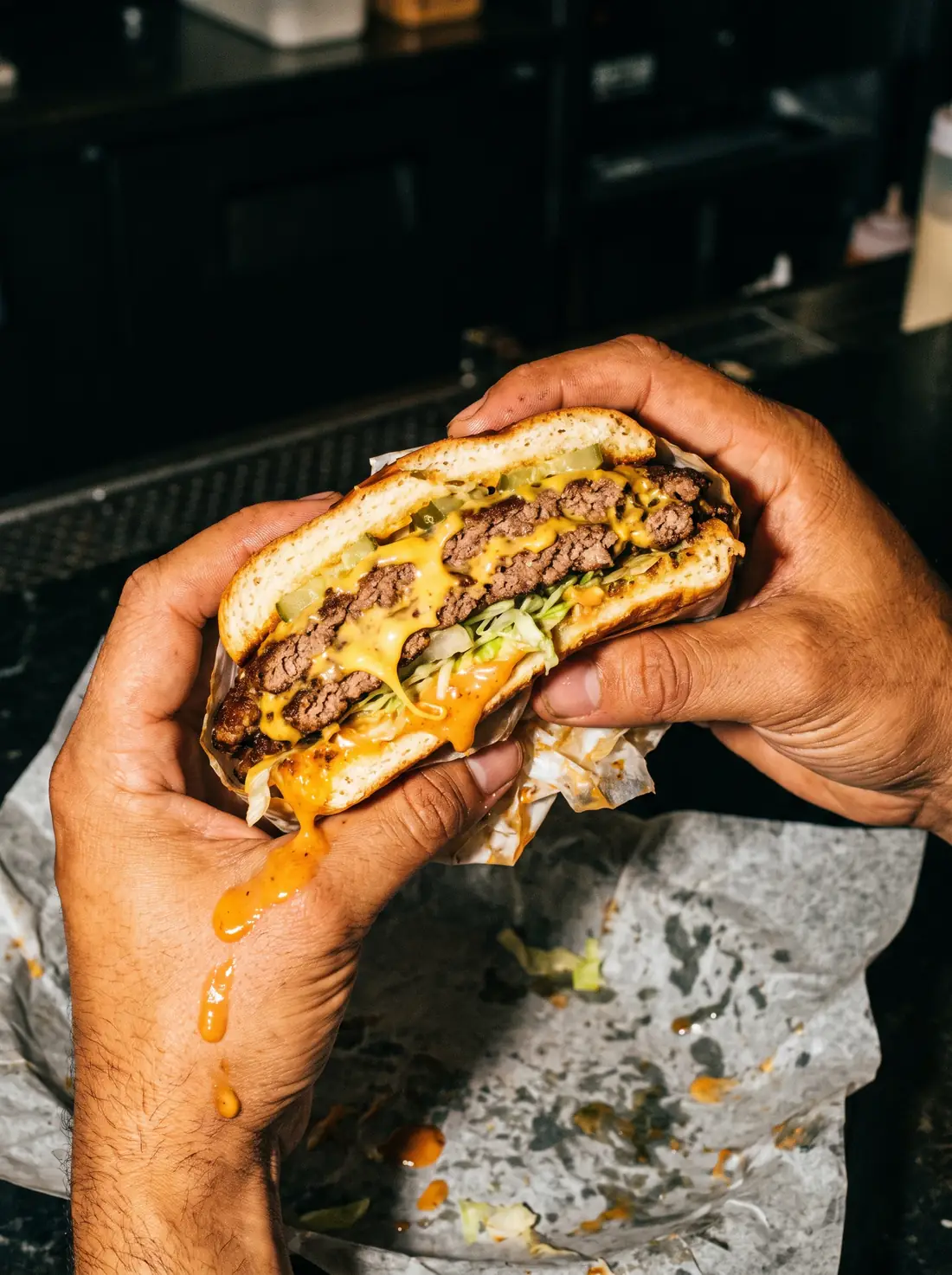 Hands holding a double smash burger cut in half